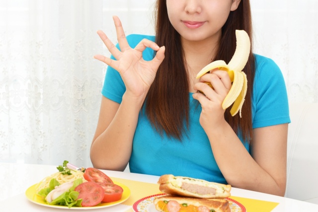 笑顔で朝食のバナナを食べる女性